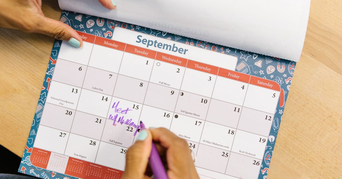 Hand writing a reminder on a September wall calendar