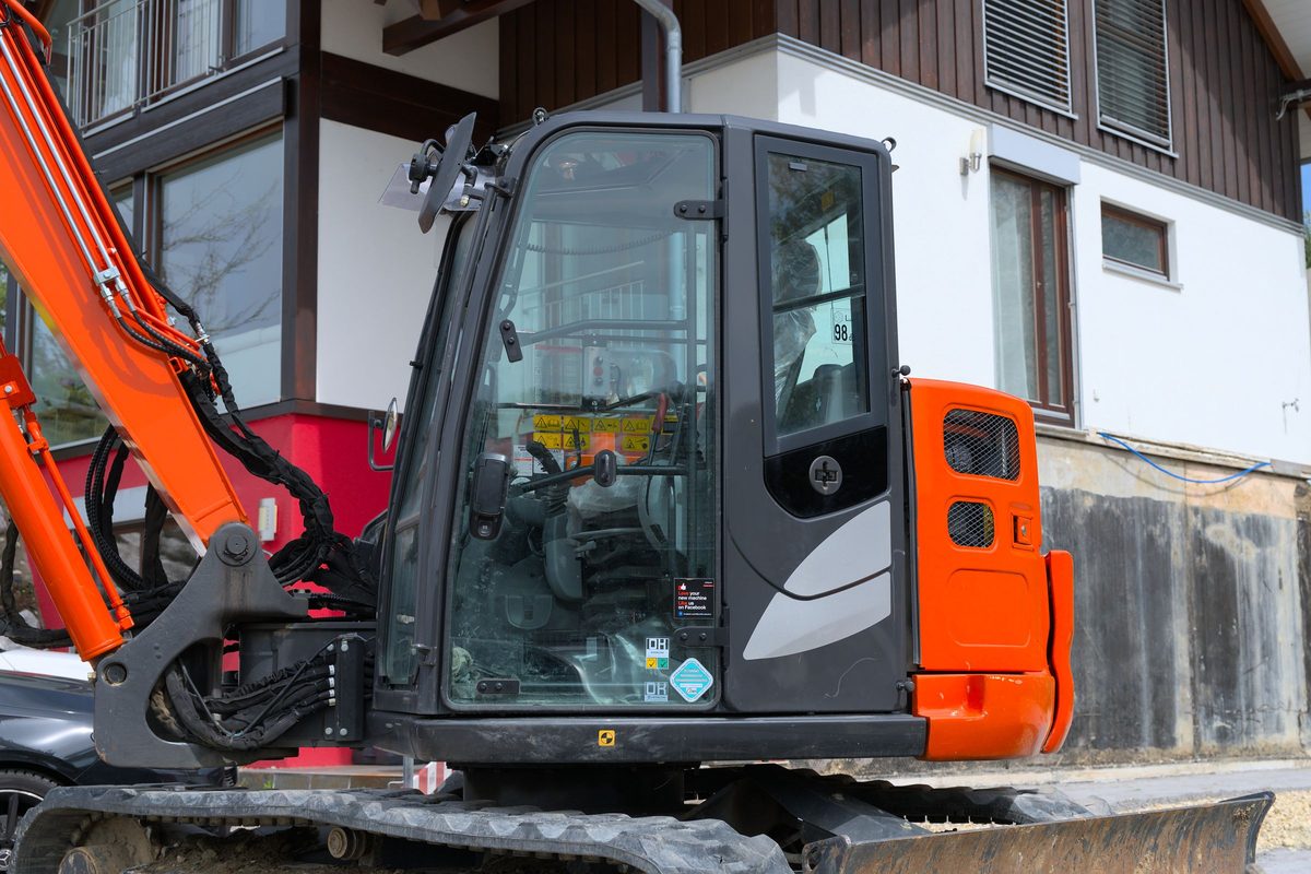 Compact excavator parked beside a house